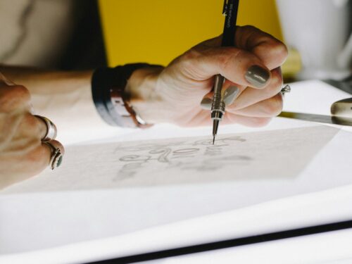 person lettering on tracing paper using mechanical pencil